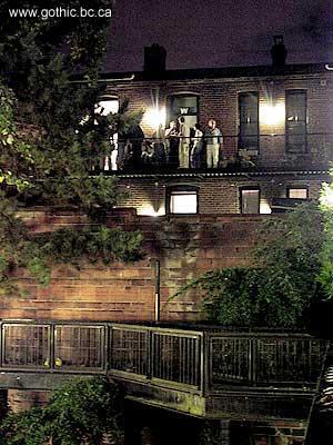 People at a loft party at the end of Blood Alley watching the balcony.